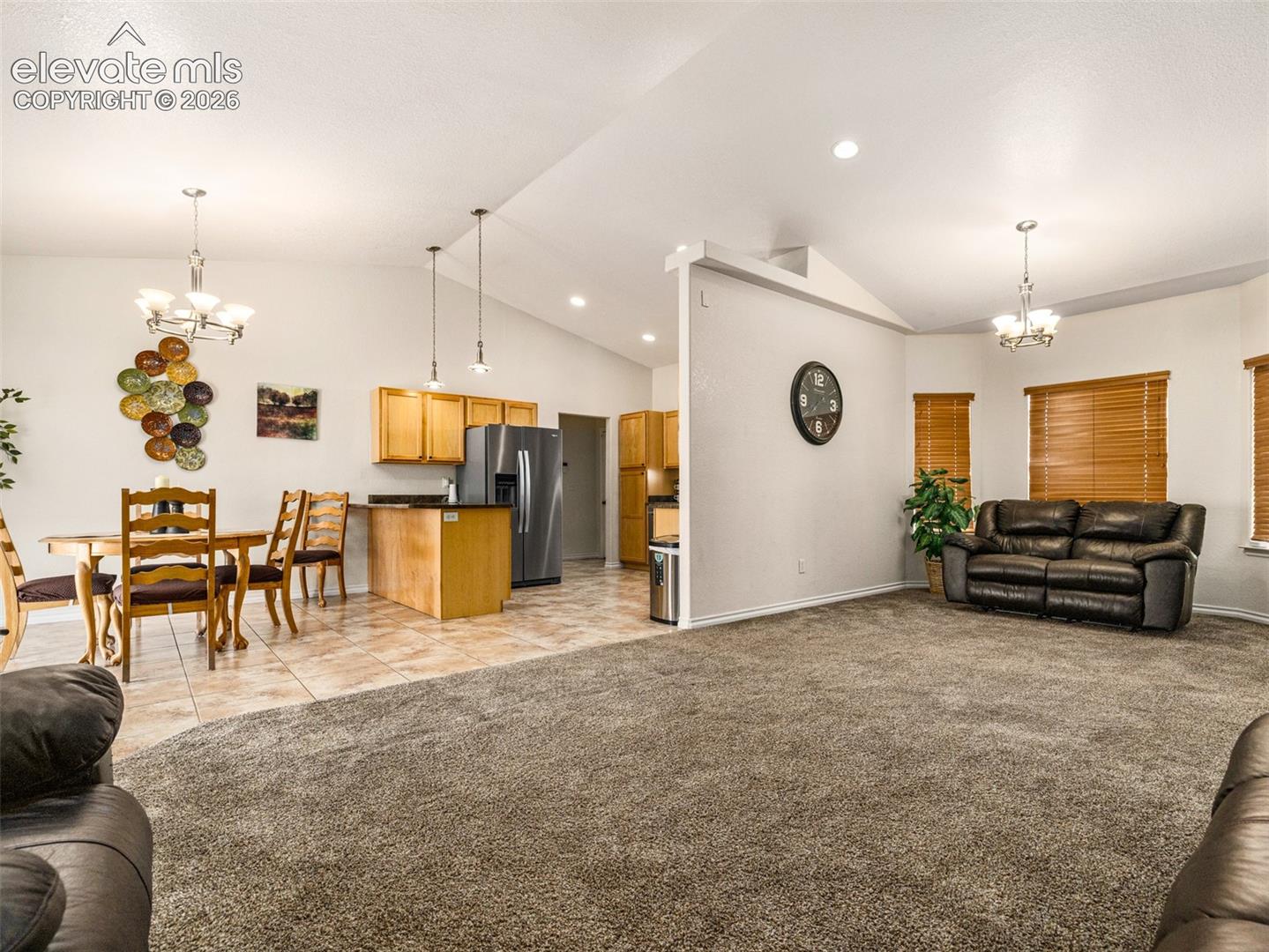 Vaulted ceilings with recessed lighting, tile flooring, wood-finish cabinetry, built-in kitchen island, and window blinds