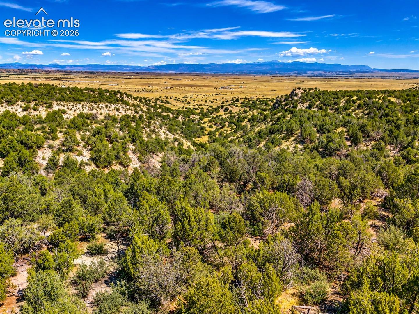 Spectacular aerial views highlighting the property's rugged ridgelines, natural ravines, and dramatic elevation changes, with expansive valley and mountain views stretching toward the horizon.

