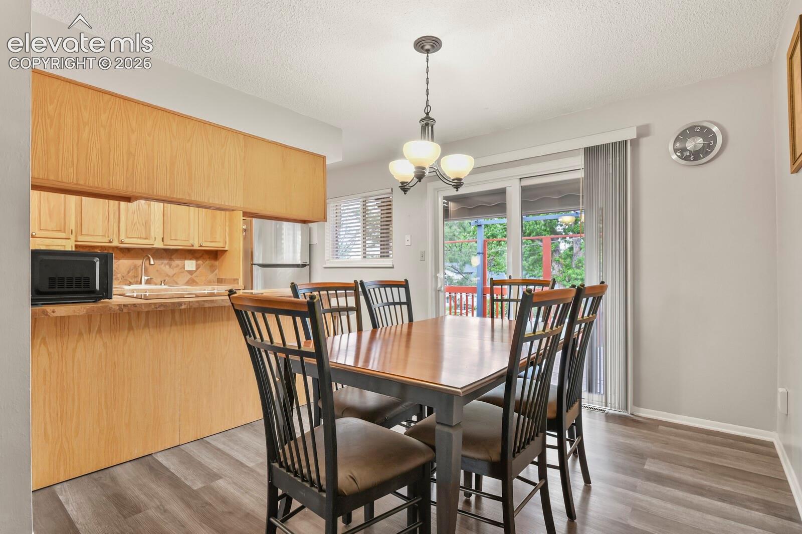 Dining area featuring wood-finish flooring, a contemporary ceiling light fixture, and a sliding glass door