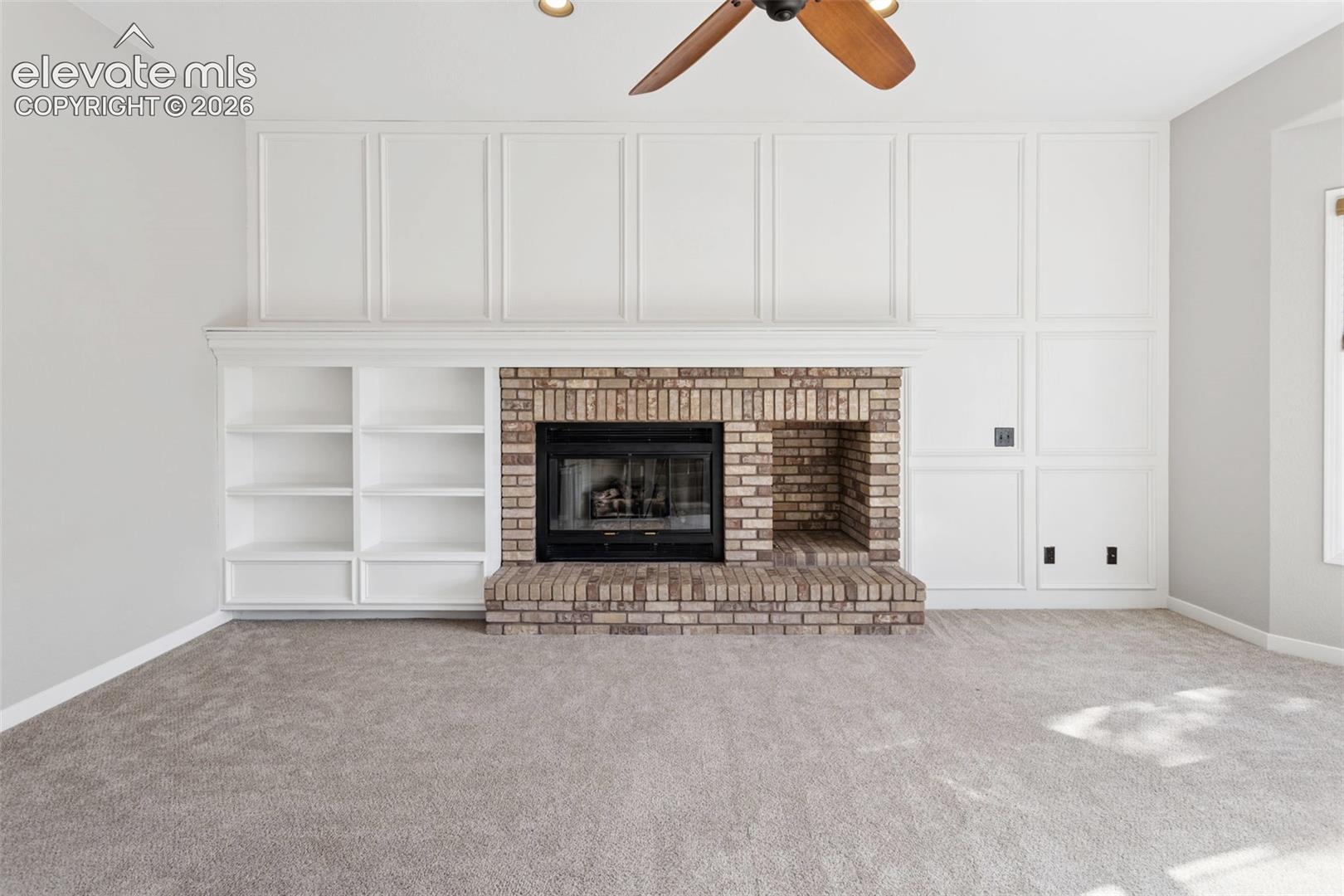 Brick fireplace with a black firebox, integrated shelving, and panel detailing