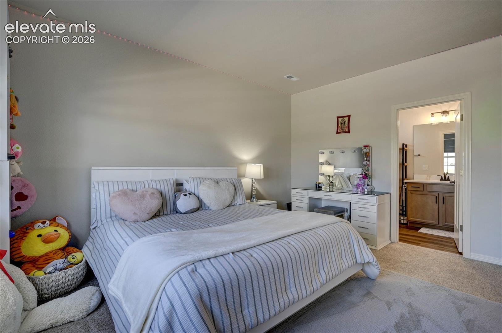 Carpeted bedroom with neutral wall tones and a white headboard
