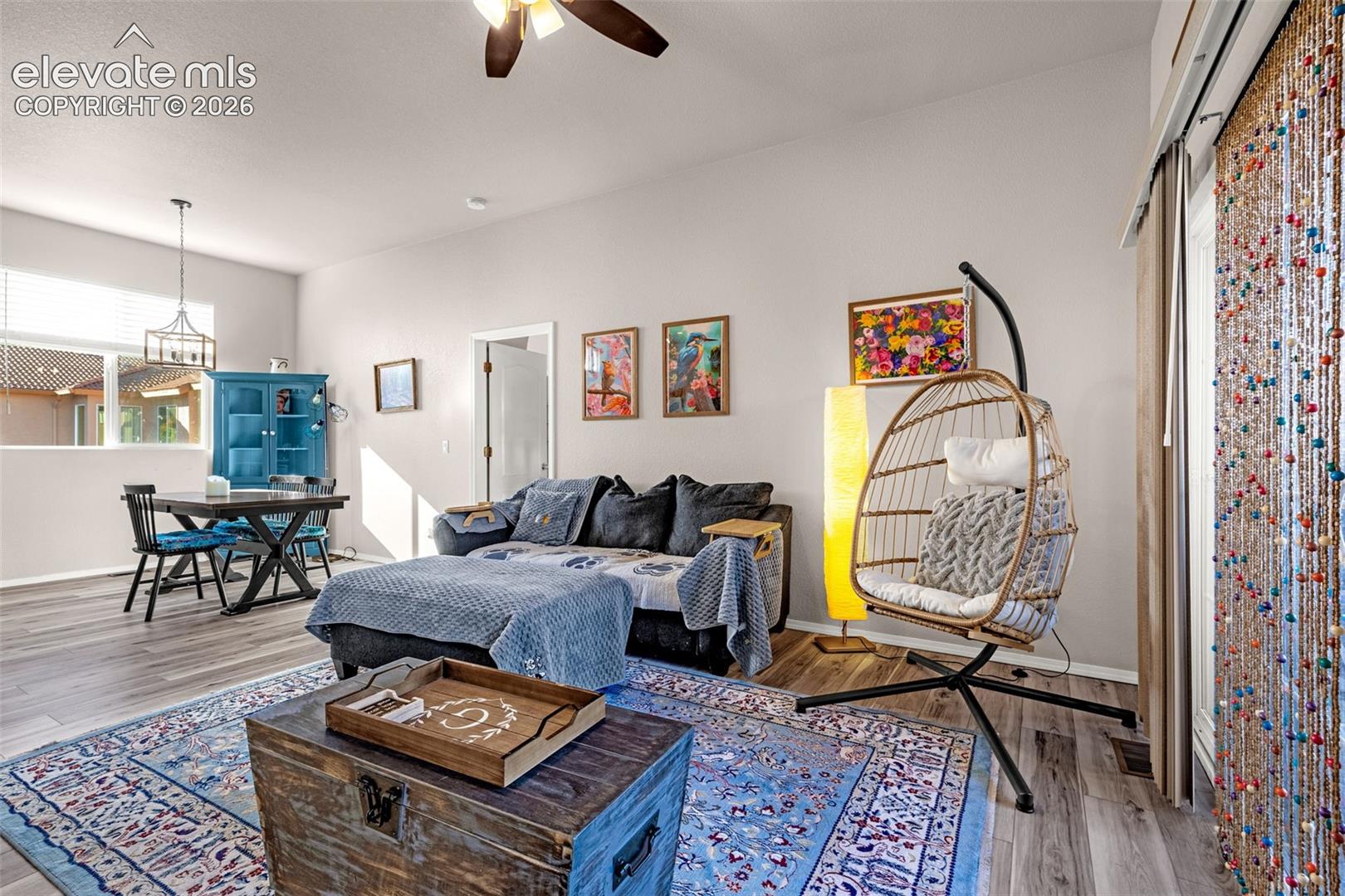 Living space featuring high ceilings, wood-finish flooring, a ceiling fan with integrated lighting, and a pendant light fixture