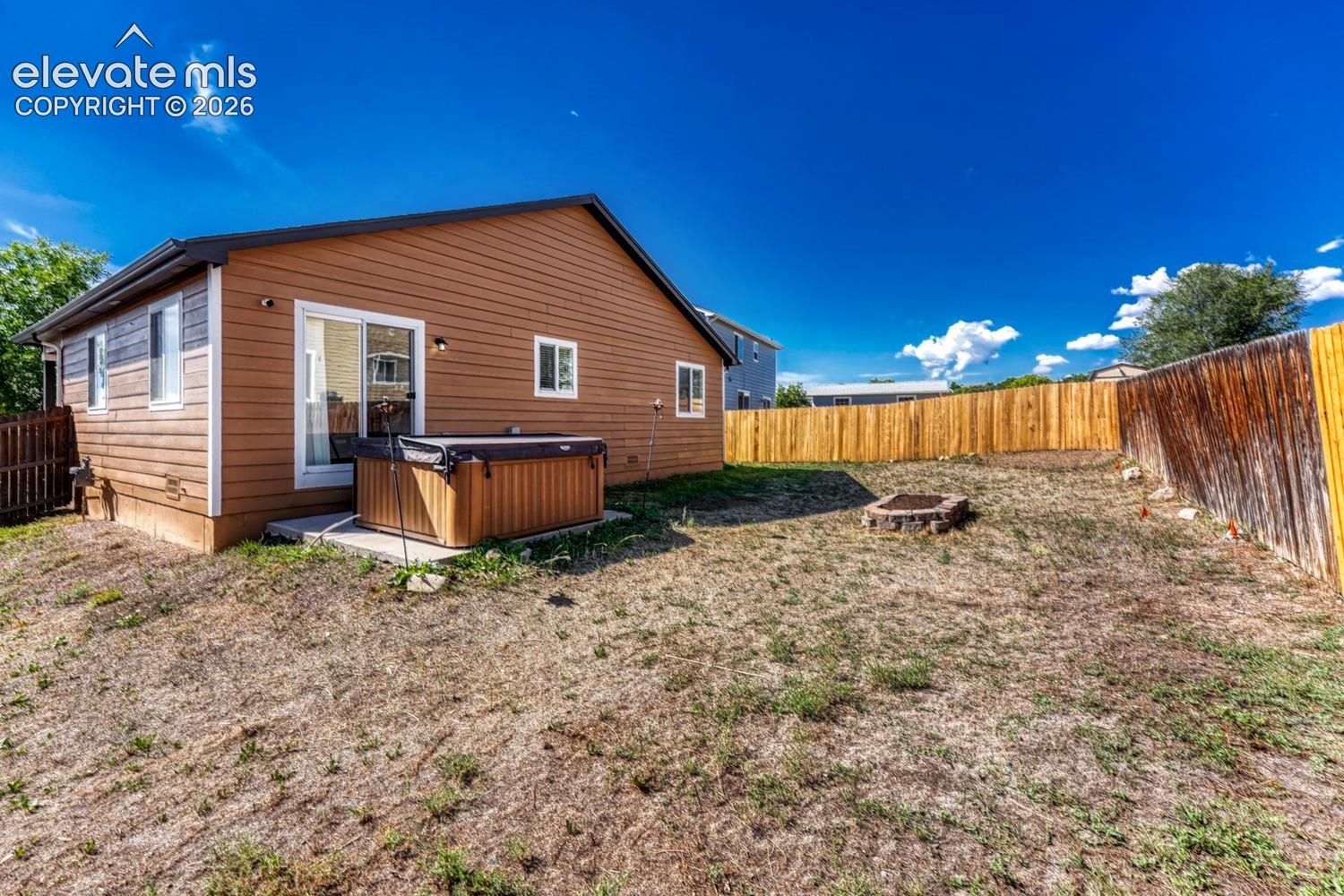 Private backyard featuring a stone fire pit, wood fencing, and a concrete patio.  Hot tub is no longer there.