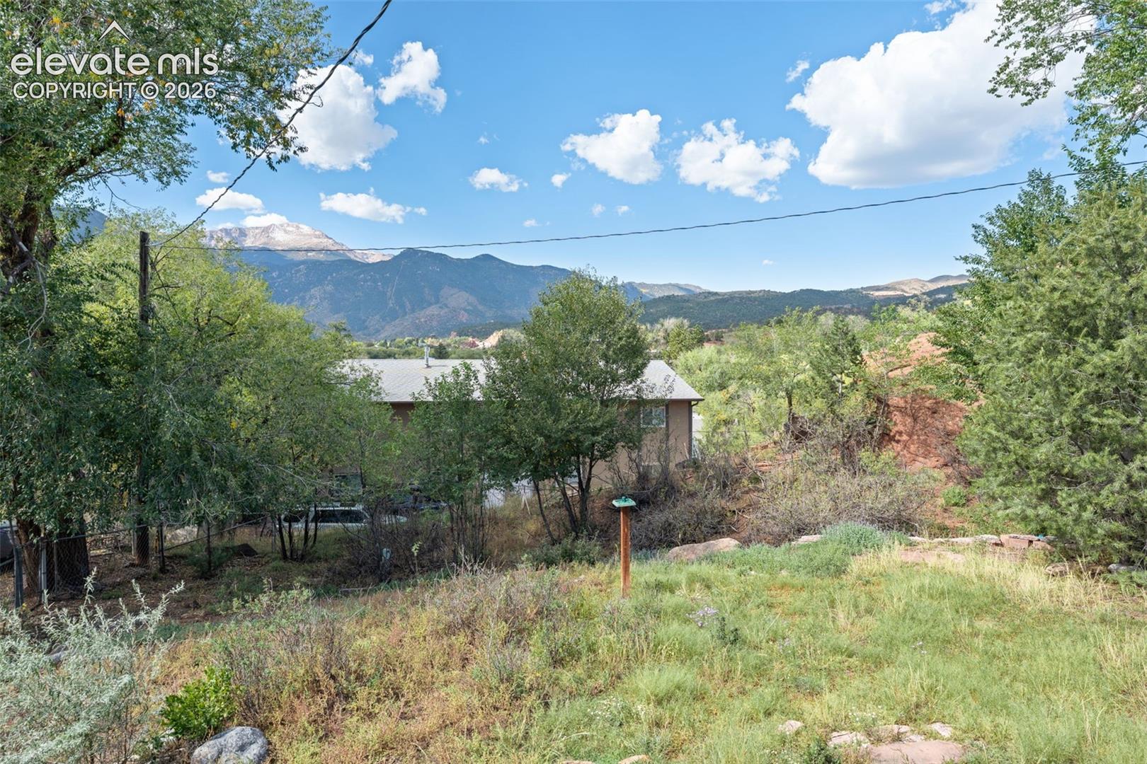 Expansive natural landscape with varied terrain and established trees, set against a backdrop of distant mountains