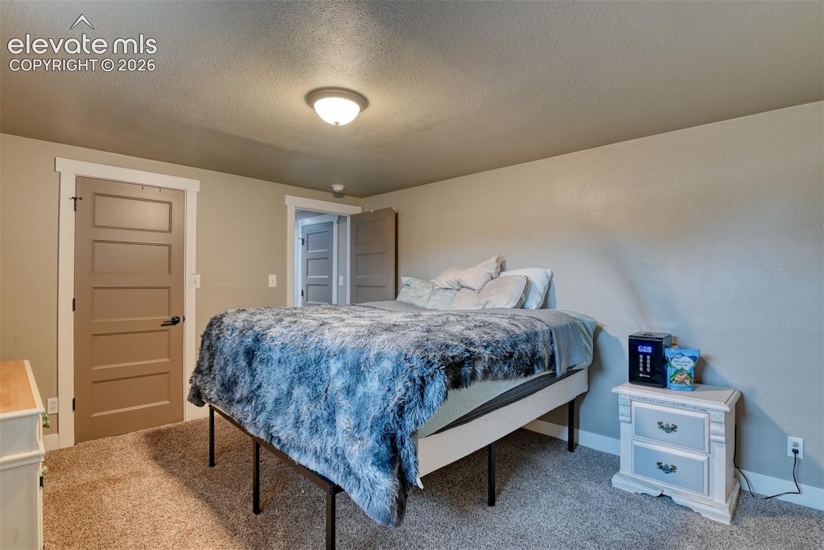 Carpeted bedroom featuring a textured ceiling and baseboards