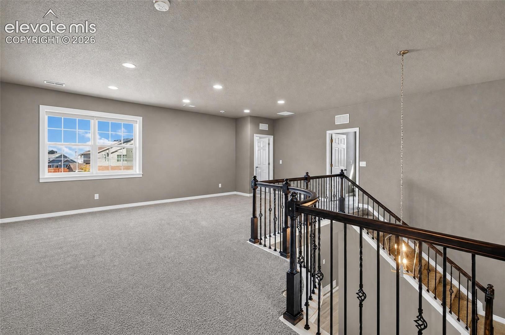 Expansive upper-level bonus room with plush carpeting, recessed lighting, and a multi-pane window