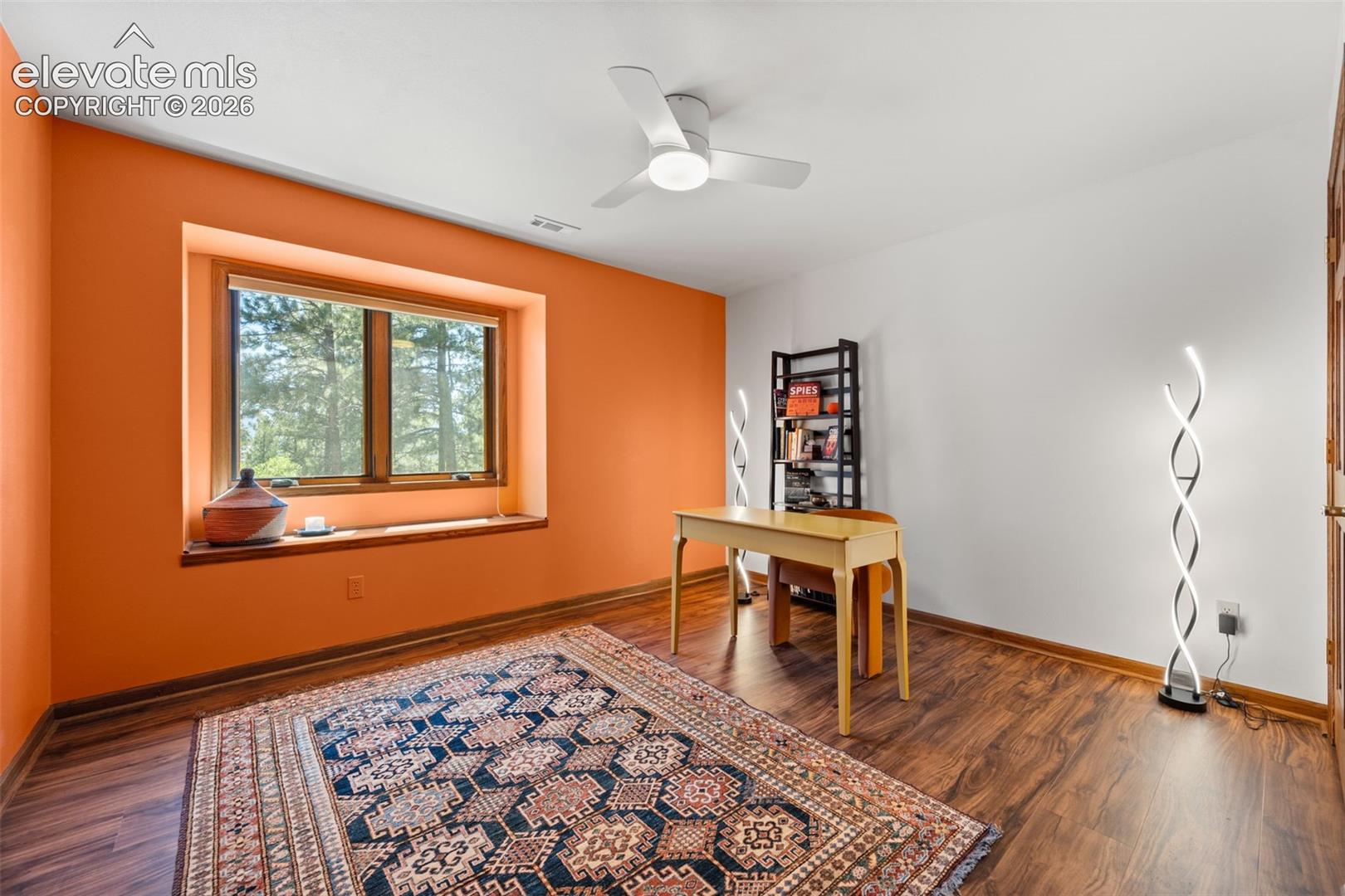 Spacious room featuring wood-finish flooring, a large window with a wood frame and sill, and a white ceiling with a modern ceiling fan