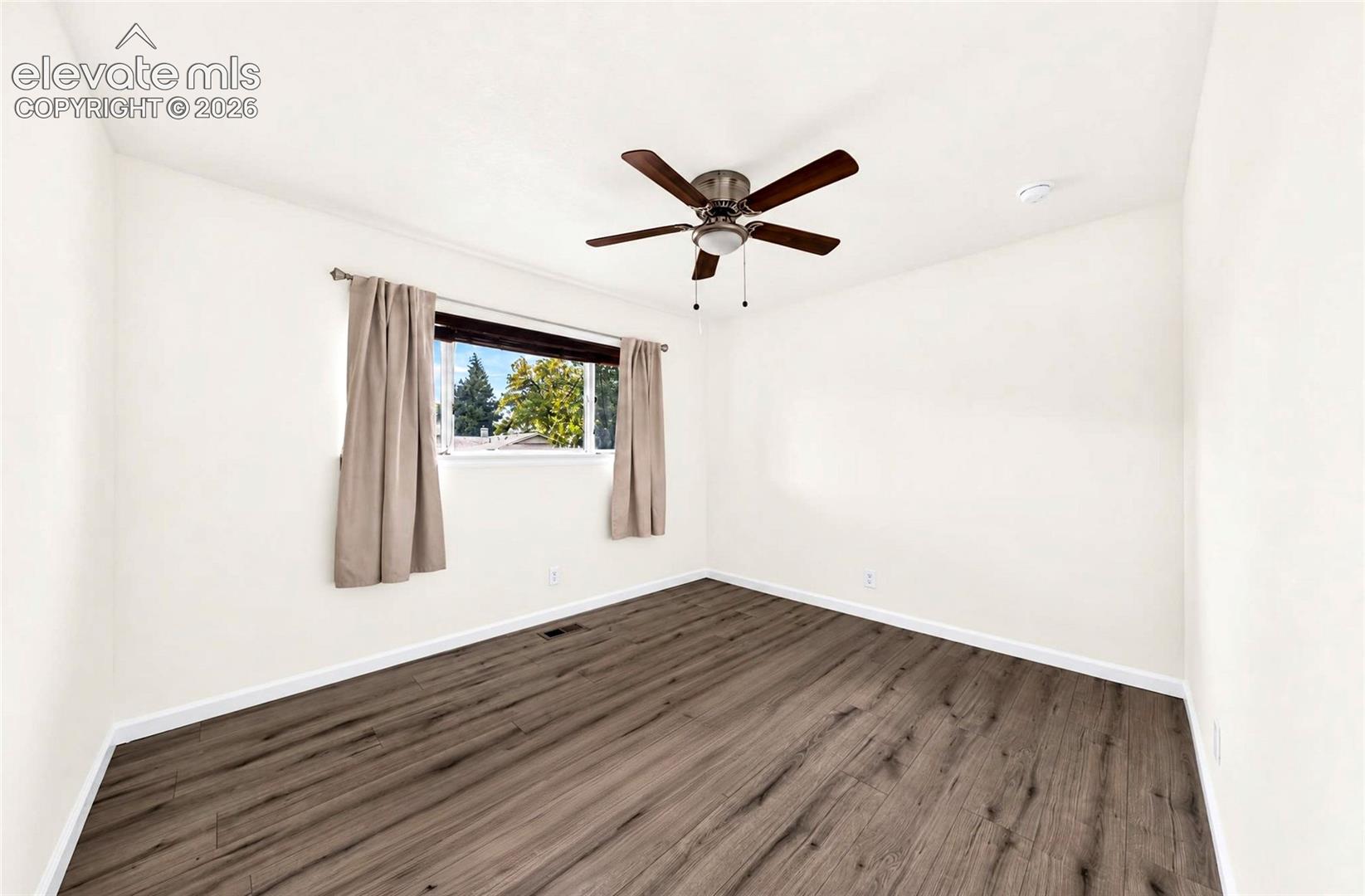 Interior room featuring wood-finish flooring, a ceiling fan with integrated lighting, and a window