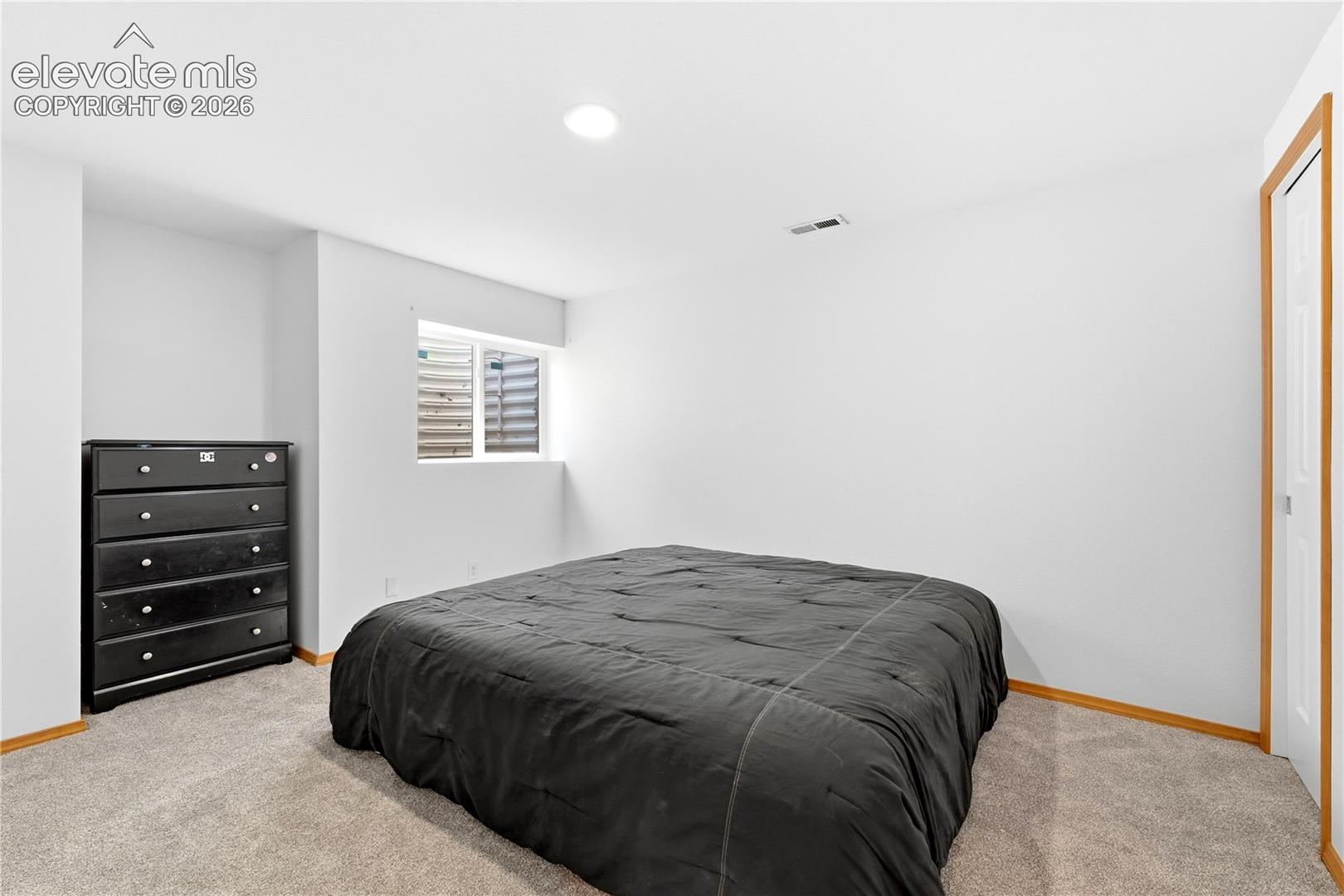 Spacious room featuring light-colored carpeting, white walls, and a window well