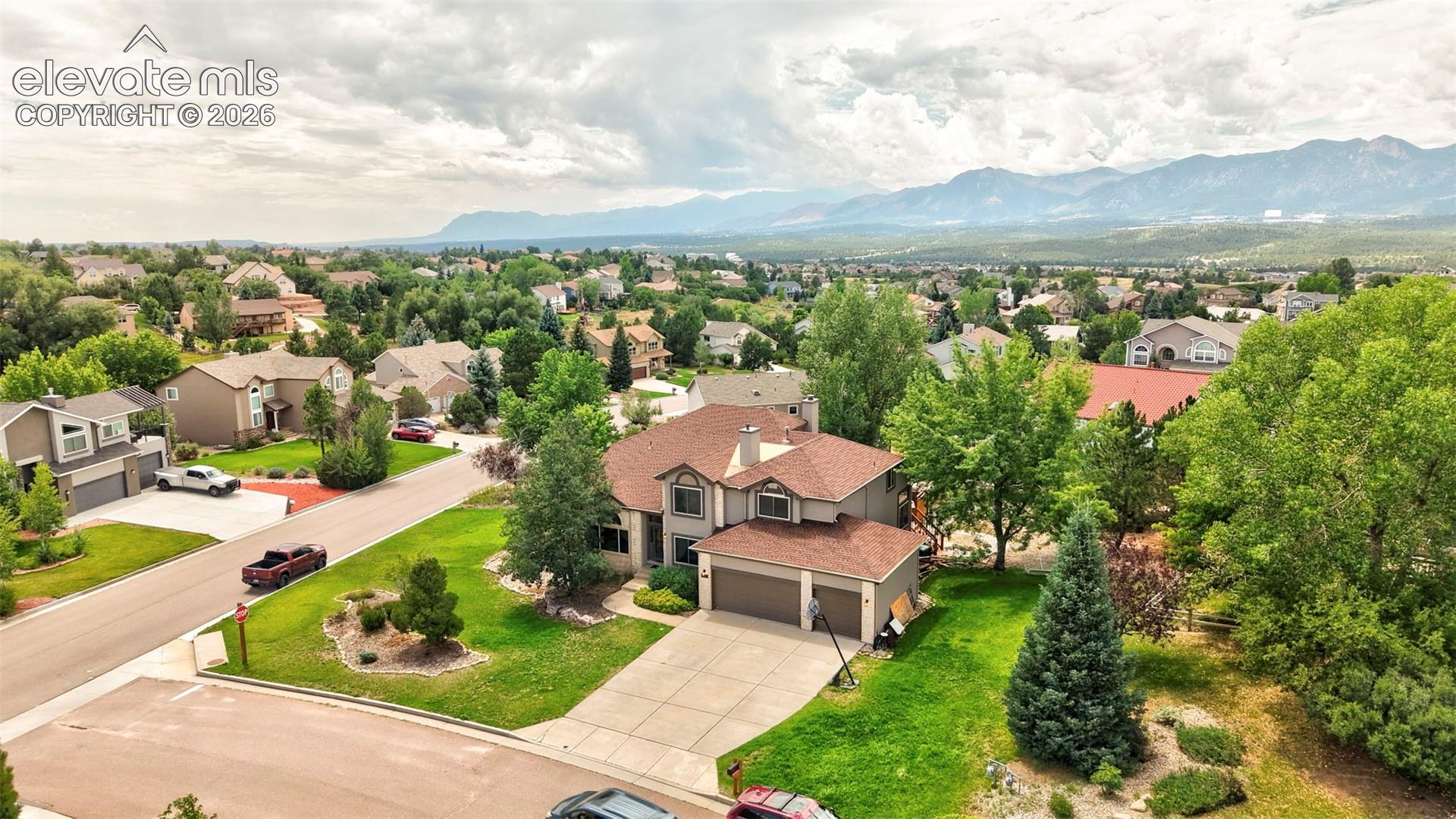 Two-story residence with a three-car garage, mature landscaping, and a paved driveway