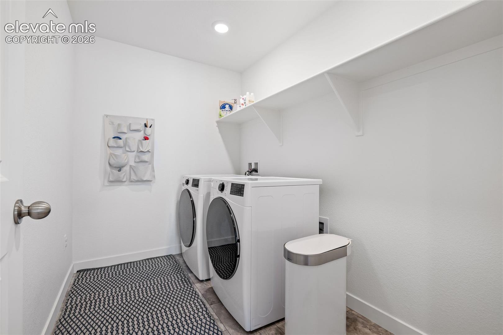 Laundry area featuring recessed lighting, extensive wall shelving, and wood-finish flooring