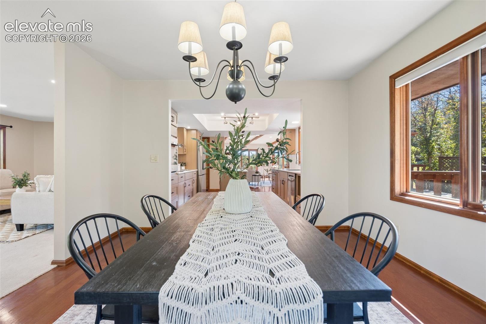 Hardwood flooring, a five-light chandelier, and a wood-framed window