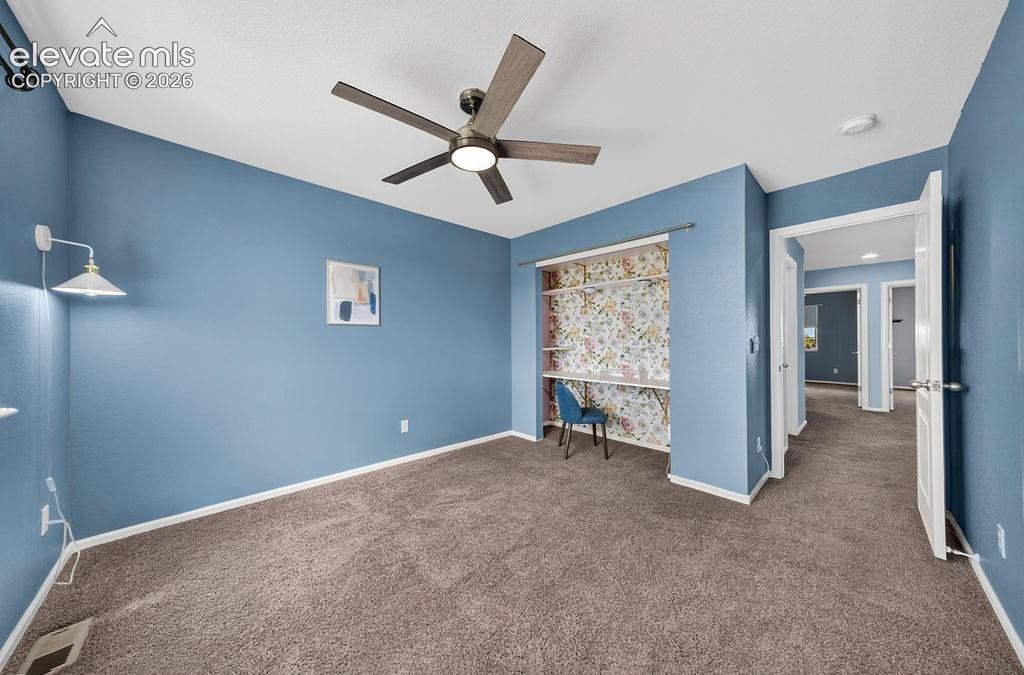 Wall-to-wall carpeting, ceiling fan with integrated lighting, built-in shelving, sconce lighting, and white trim