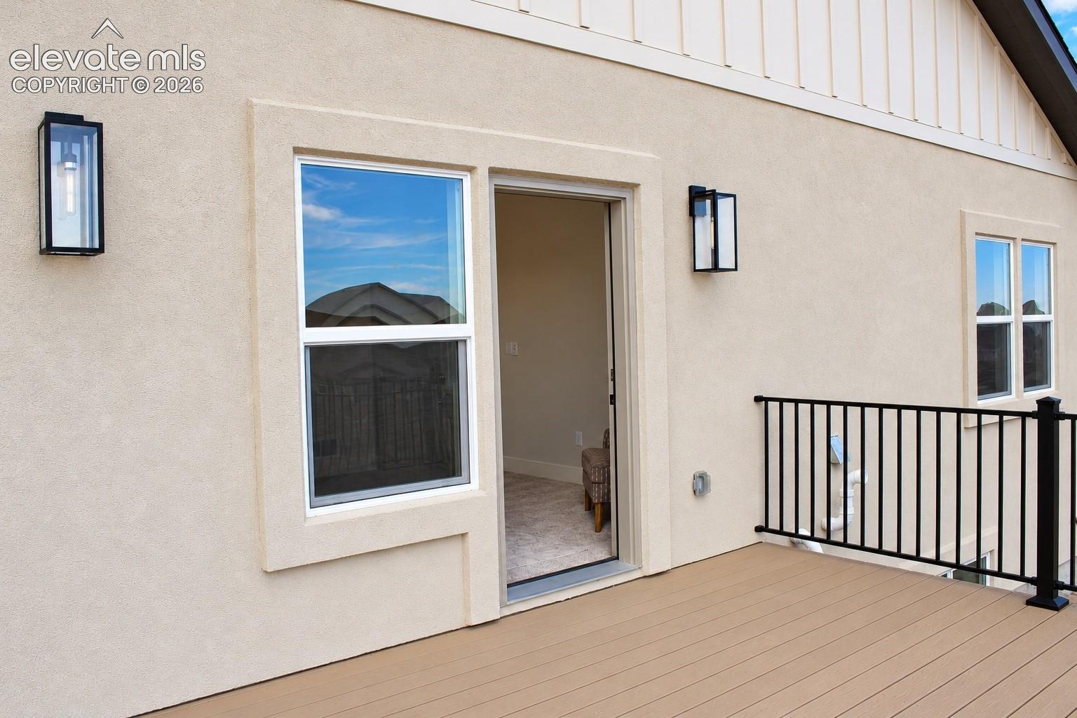Exterior deck with composite decking, black metal railing, and stucco siding