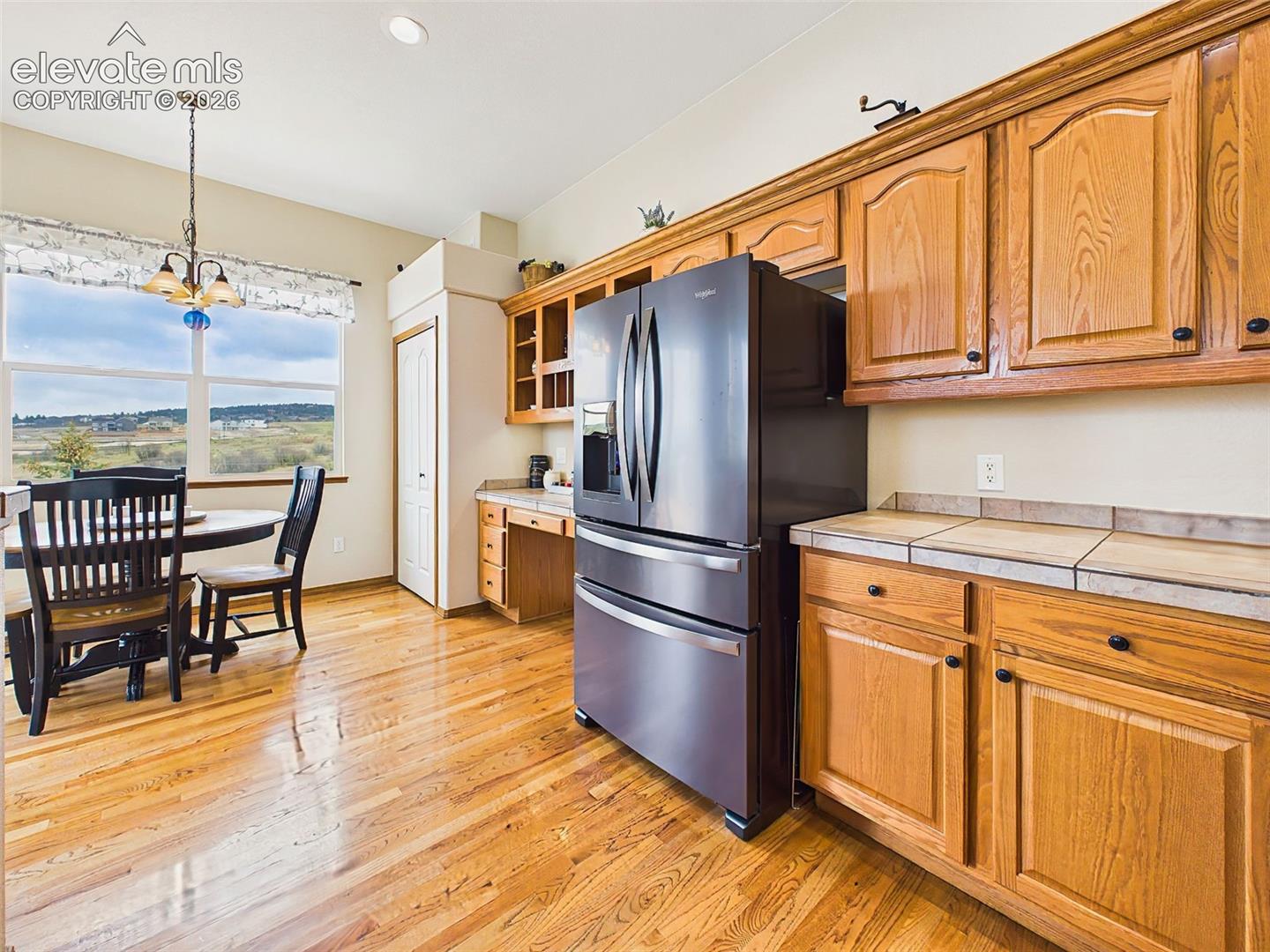 Light-filled kitchen and breakfast nook overlooking scenic open space views through oversized windows and glass doors.