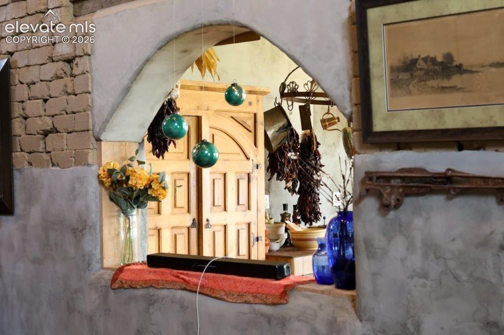 Arched interior window with a deep sill, featuring textured adobe walls and exposed adobe brickwork