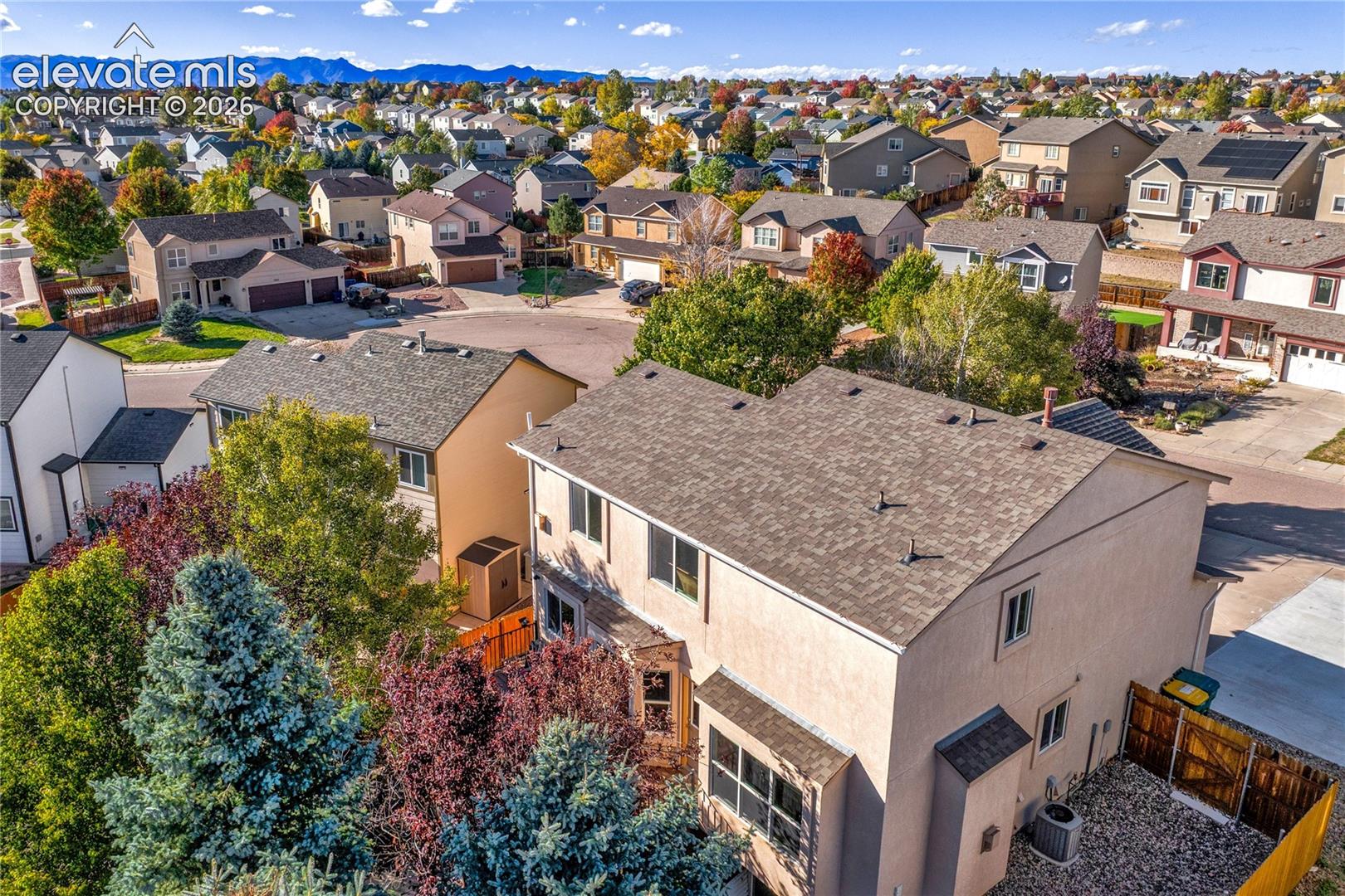 An elevated perspective highlights the home's mature trees, established landscaping + outdoor spaces, with the surrounding neighborhood and Front Range beyond.