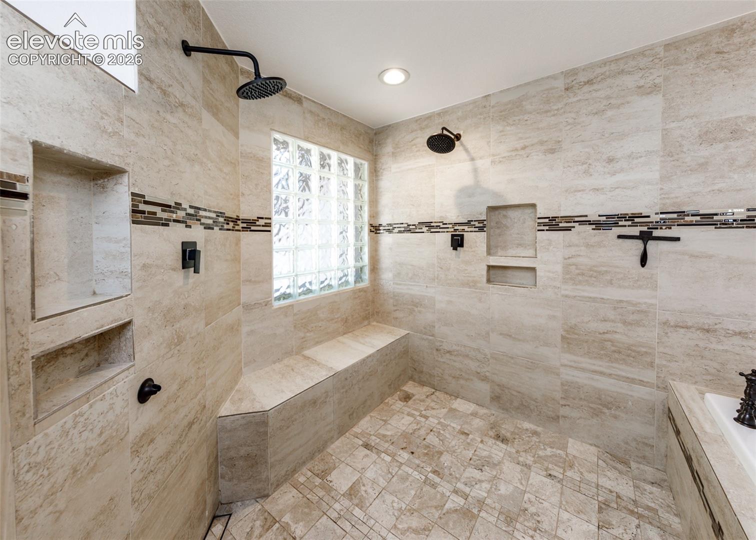 Master bathroom two head shower with a large bench