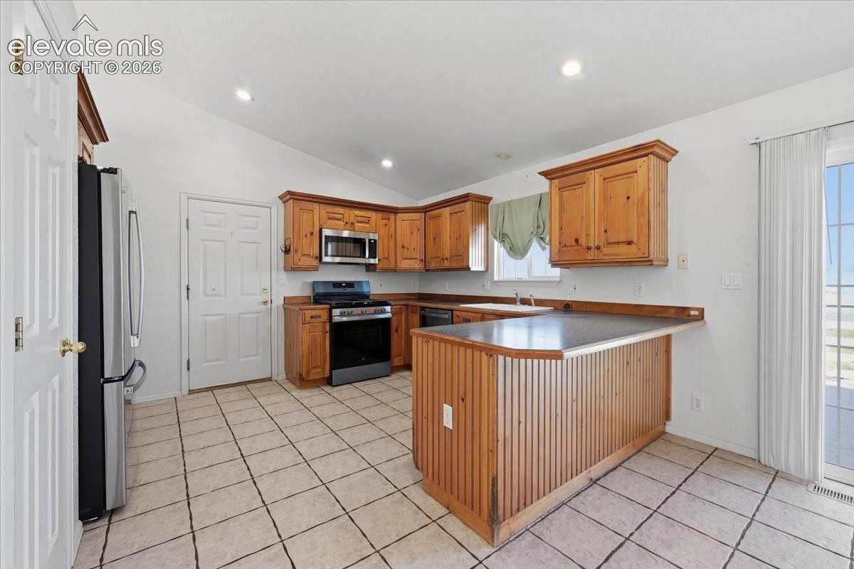 Kitchen featuring wood cabinetry, stainless steel microwave, and tile flooring