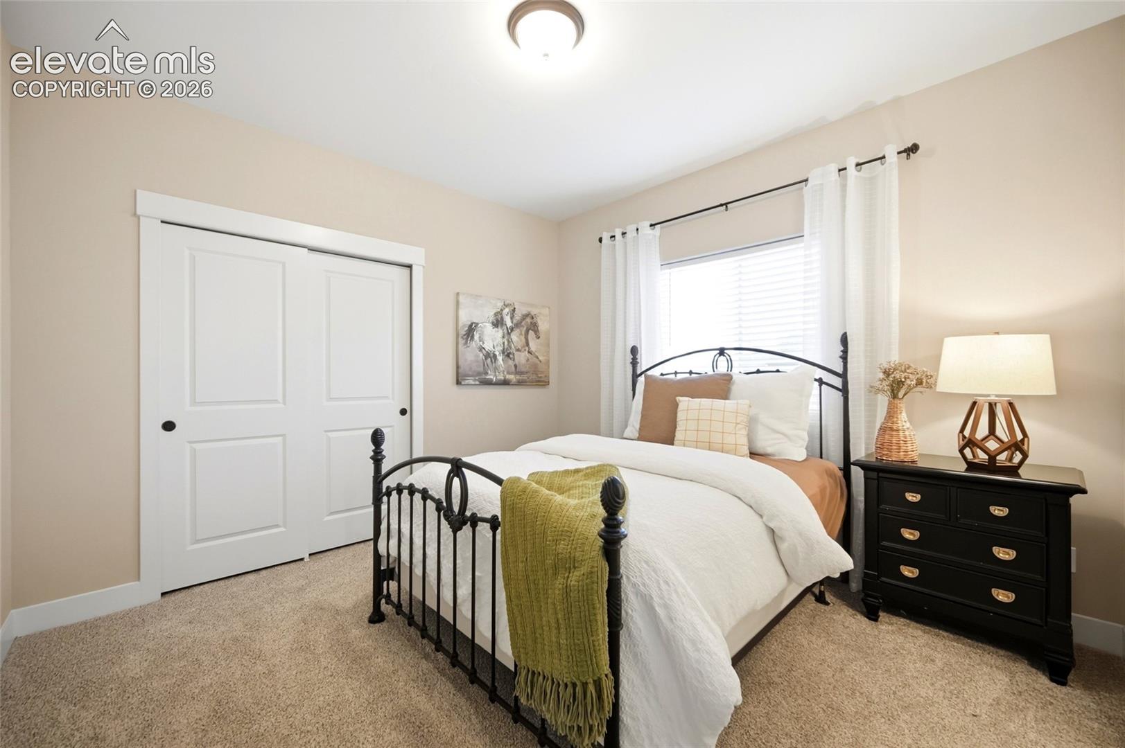 Neutral-toned bedroom featuring plush wall-to-wall carpeting, white two-panel sliding closet doors, and a ceiling-mounted flush light fixture