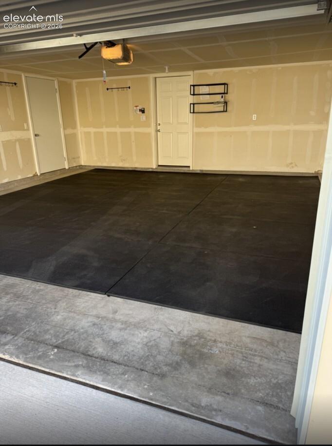 Two-car garage featuring matte-finish flooring, drywall-finished interior walls, and two access doors