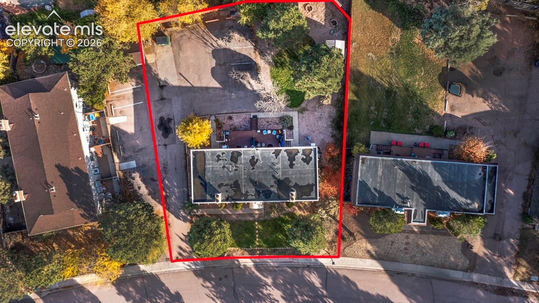 Aerial perspective of property lot featuring an expansive backyard, mature landscaping, paved driveway, and detached structure