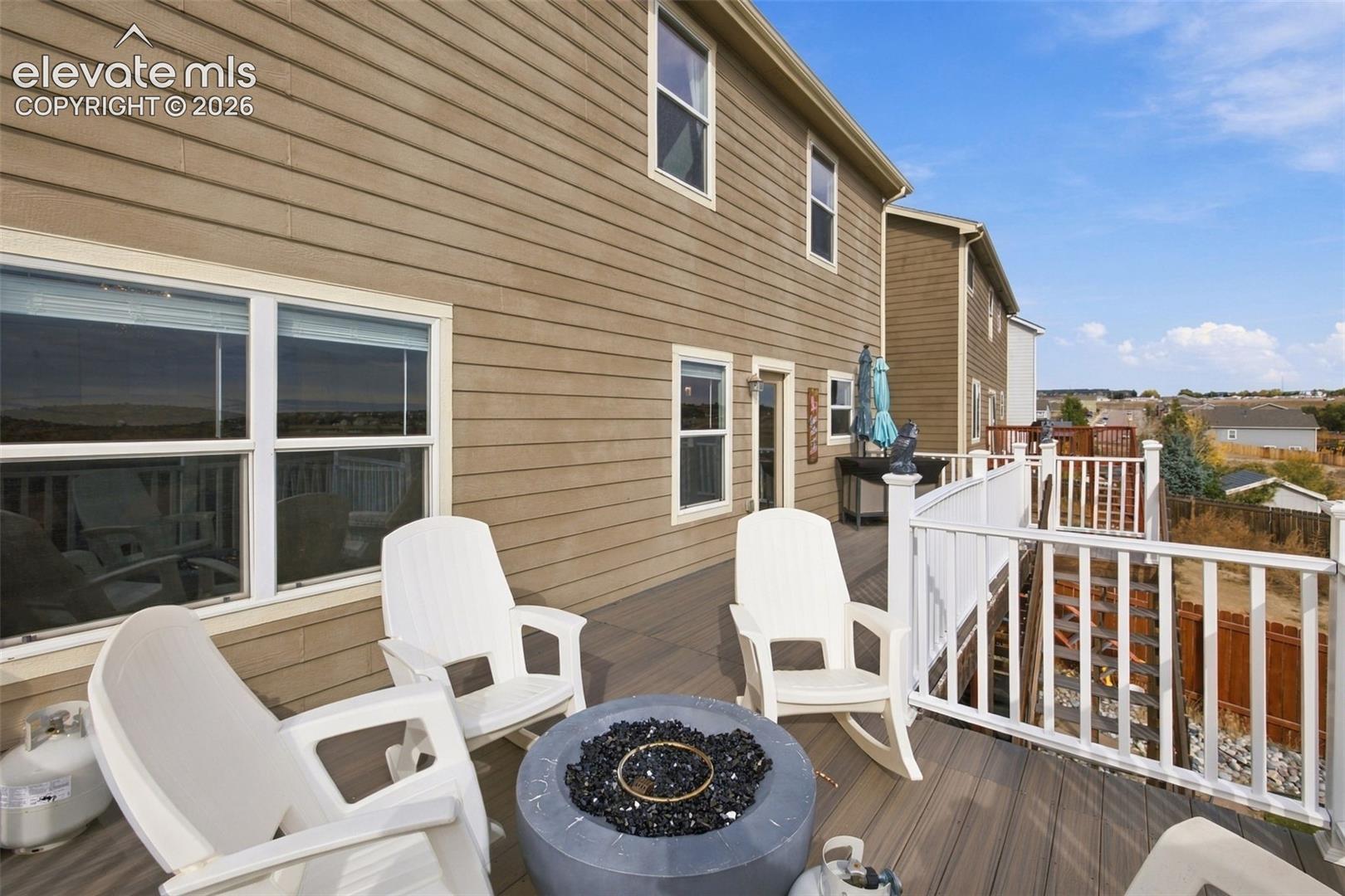 Elevated composite deck featuring white railings, horizontal lap siding, and multi-pane windows