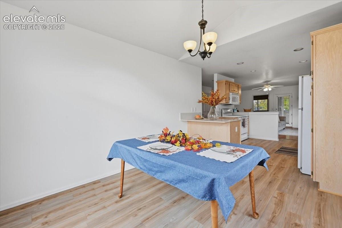 Wood-finish flooring, three-light metal chandelier, and neutral wall tones