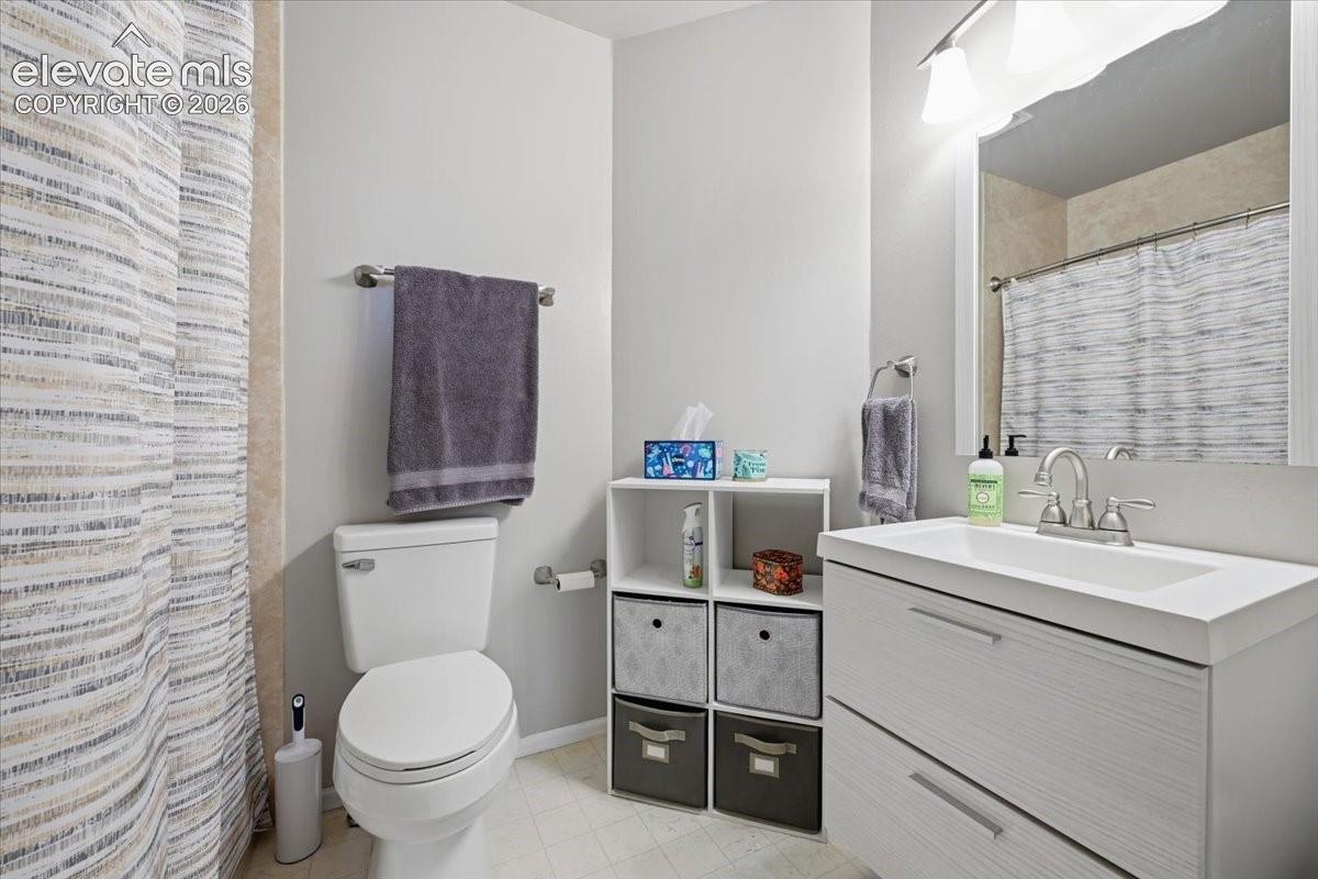 Bathroom featuring a white vanity with integrated basin, polished metal faucet, wall-mounted light fixture, large vanity mirror, and bathtub enclosure