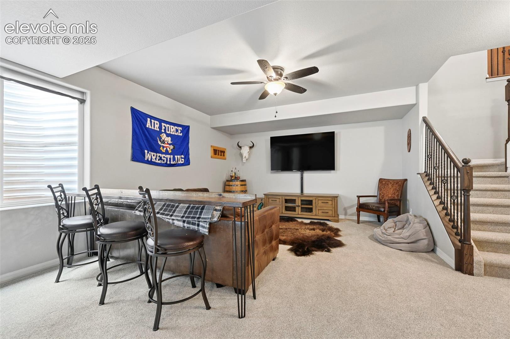 Interior space featuring neutral carpeting and a staircase with metal balusters and a wood handrail