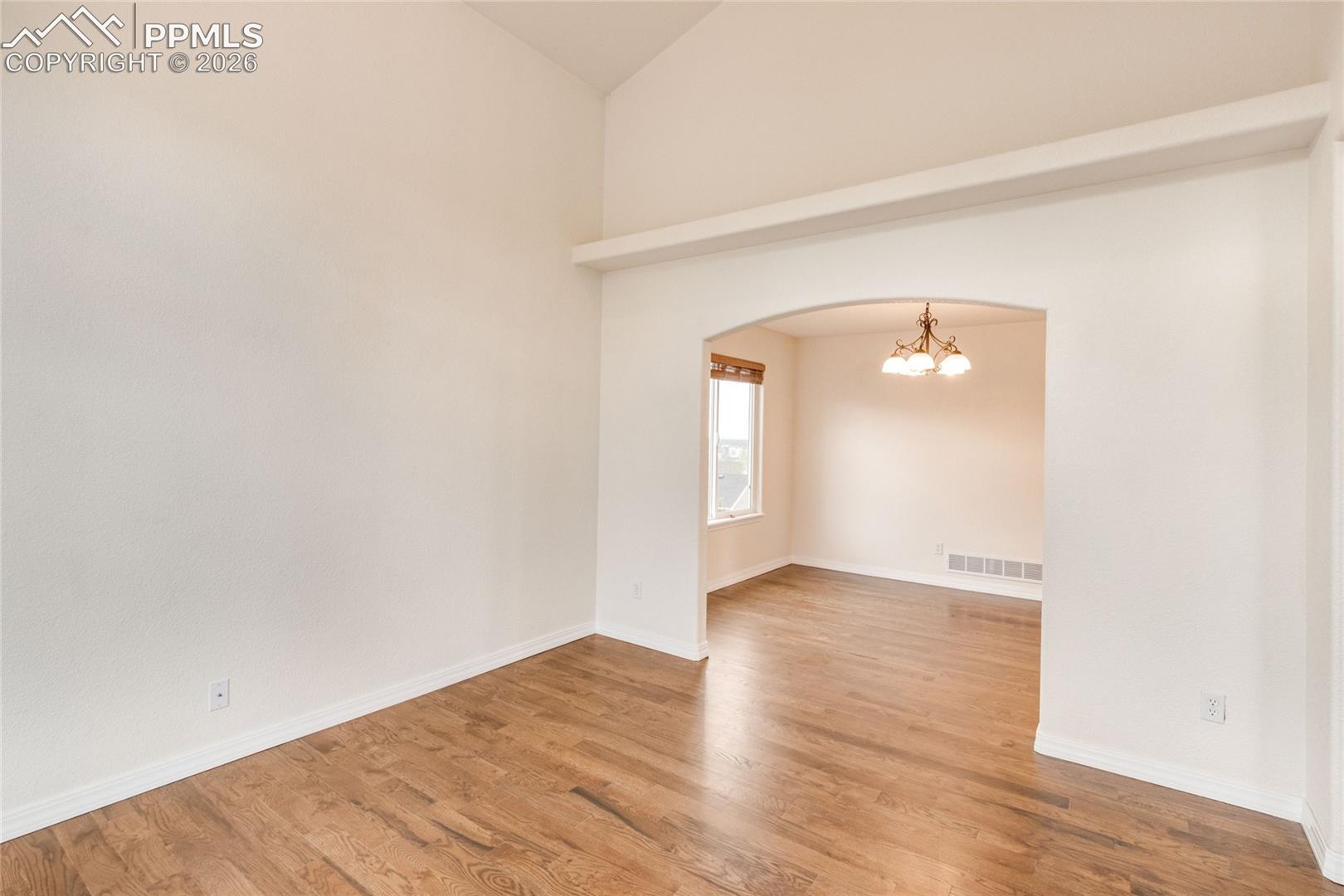 Living room featuring wood-finish flooring and arch doorway to dining room.