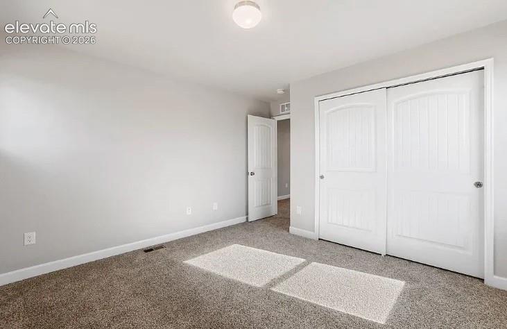 Room featuring neutral wall tones, plush wall-to-wall carpeting, white-paneled closet doors, and flush-mount ceiling lighting