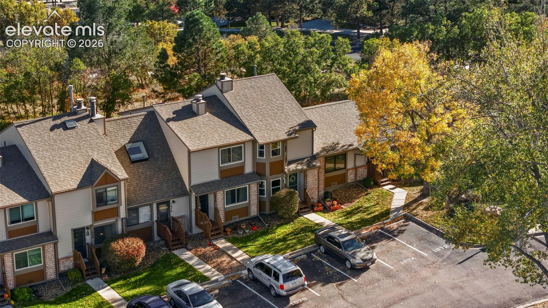 Multi-level building with shingled roofing, lap siding, bay windows, and designated surface parking