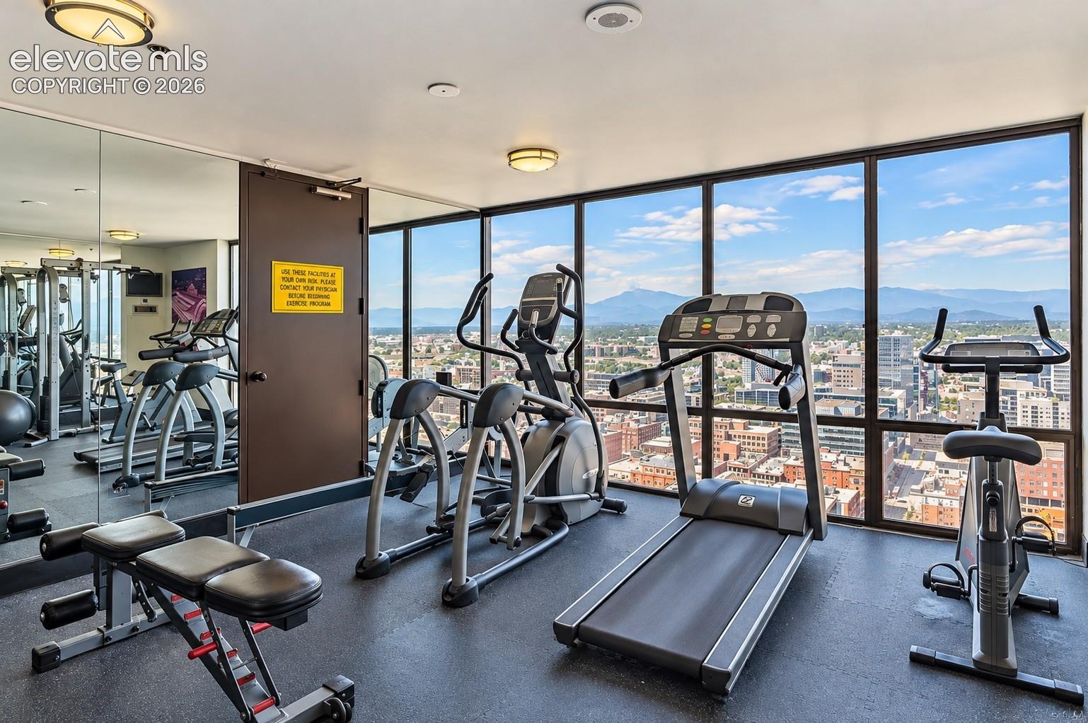 Fitness center featuring floor-to-ceiling windows, city scenery, and mountain backdrop