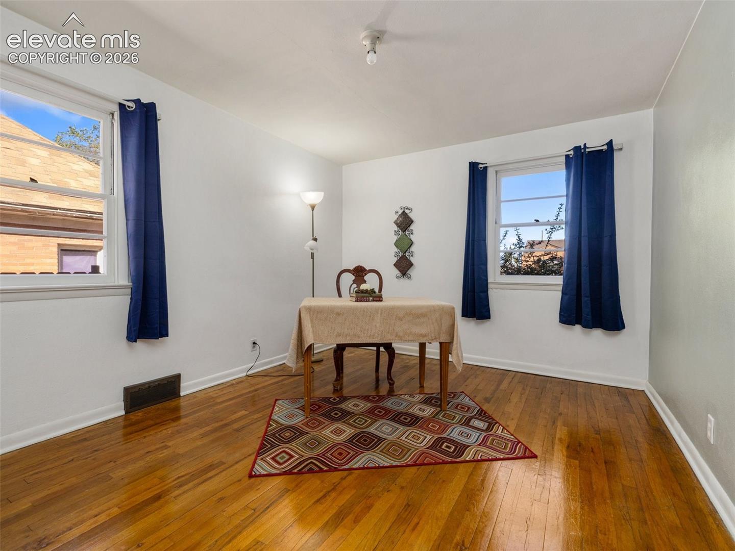 Interior space featuring wood-finish flooring, two large windows, and neutral walls