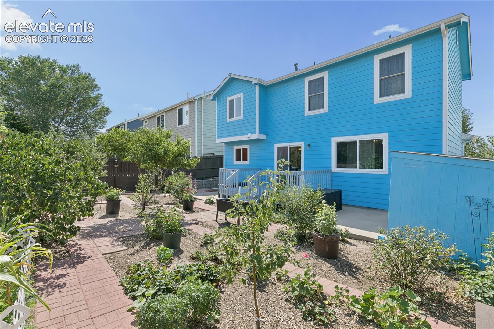Expansive yard featuring a brick paver pathway, established garden beds, and mature trees