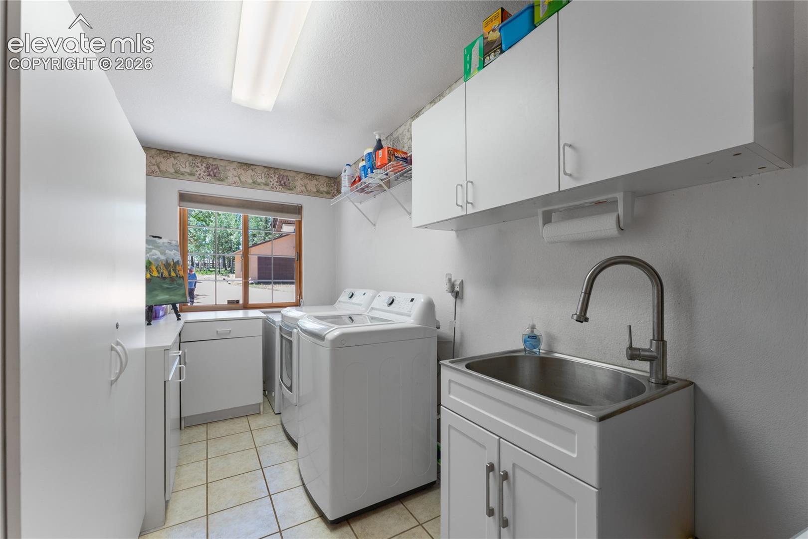 Utility room with white cabinetry, tile flooring, and a stainless steel utility sink with a high-arch faucet