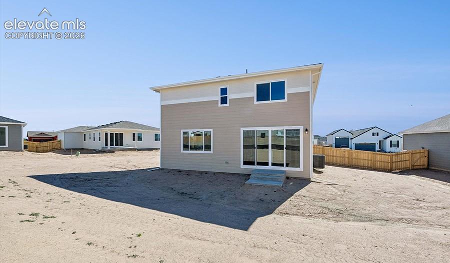 Two-story exterior with horizontal siding, sliding glass doors, concrete step, and fenced perimeter