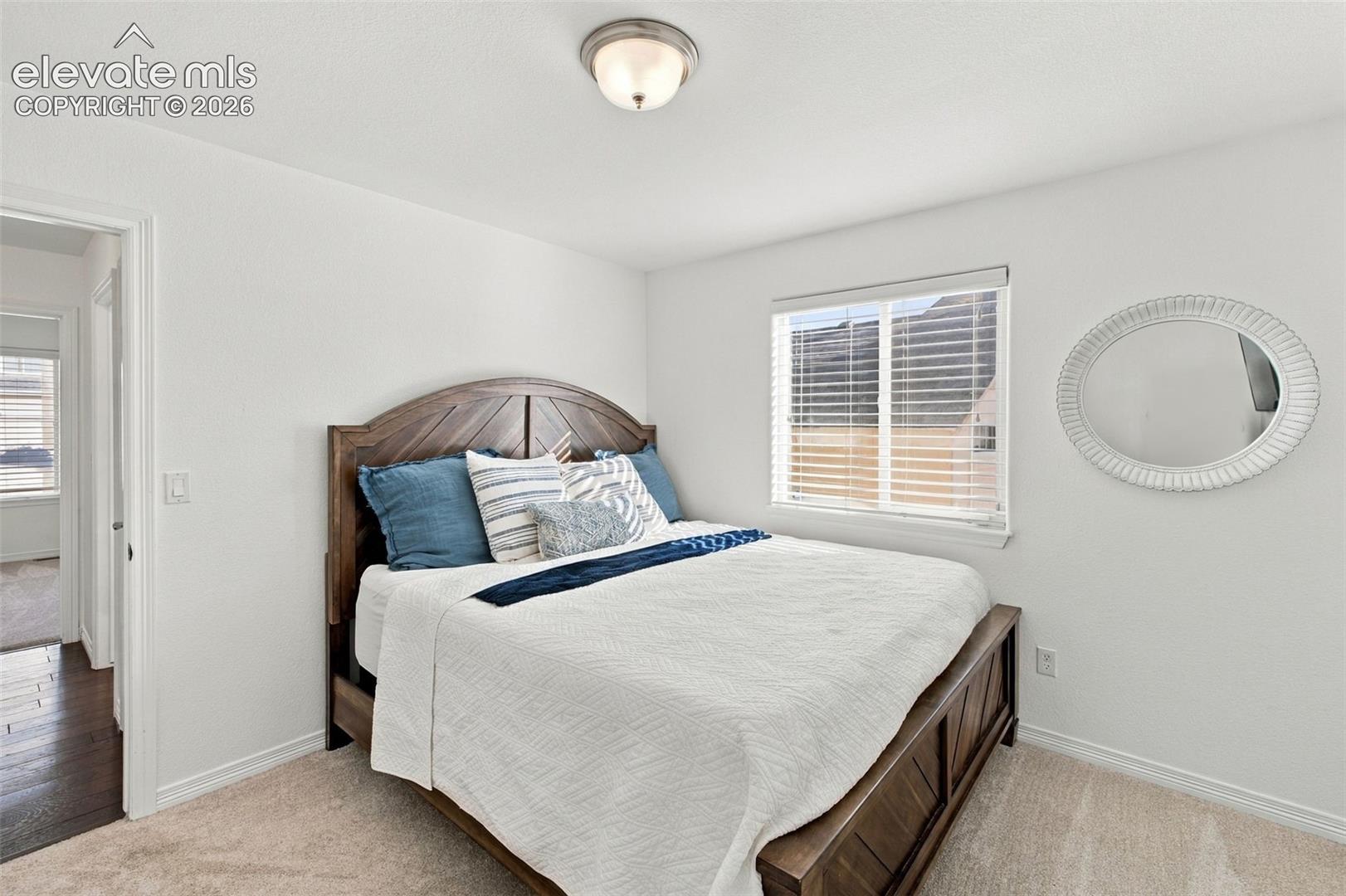 Neutral-toned carpeting, flush-mount ceiling light fixture, and horizontal window blinds