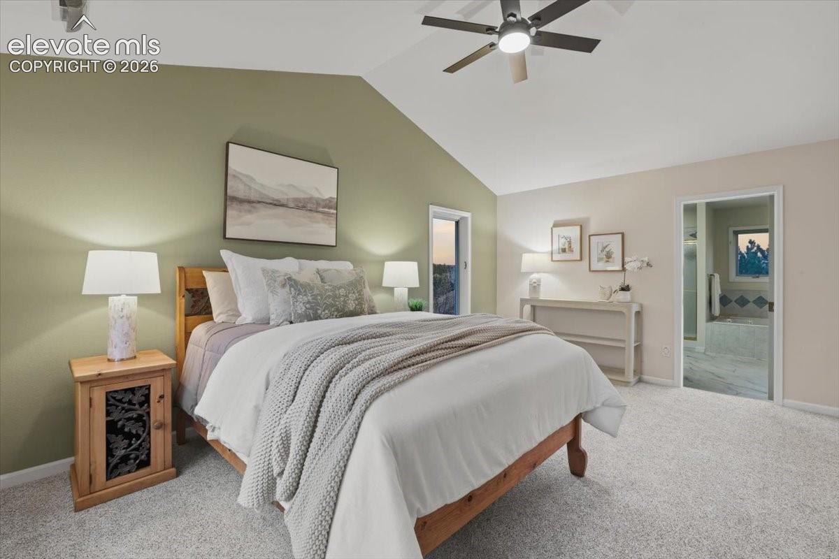 Vaulted ceiling with a ceiling fan, carpeted flooring, and an open doorway to an adjacent room with a built-in tub