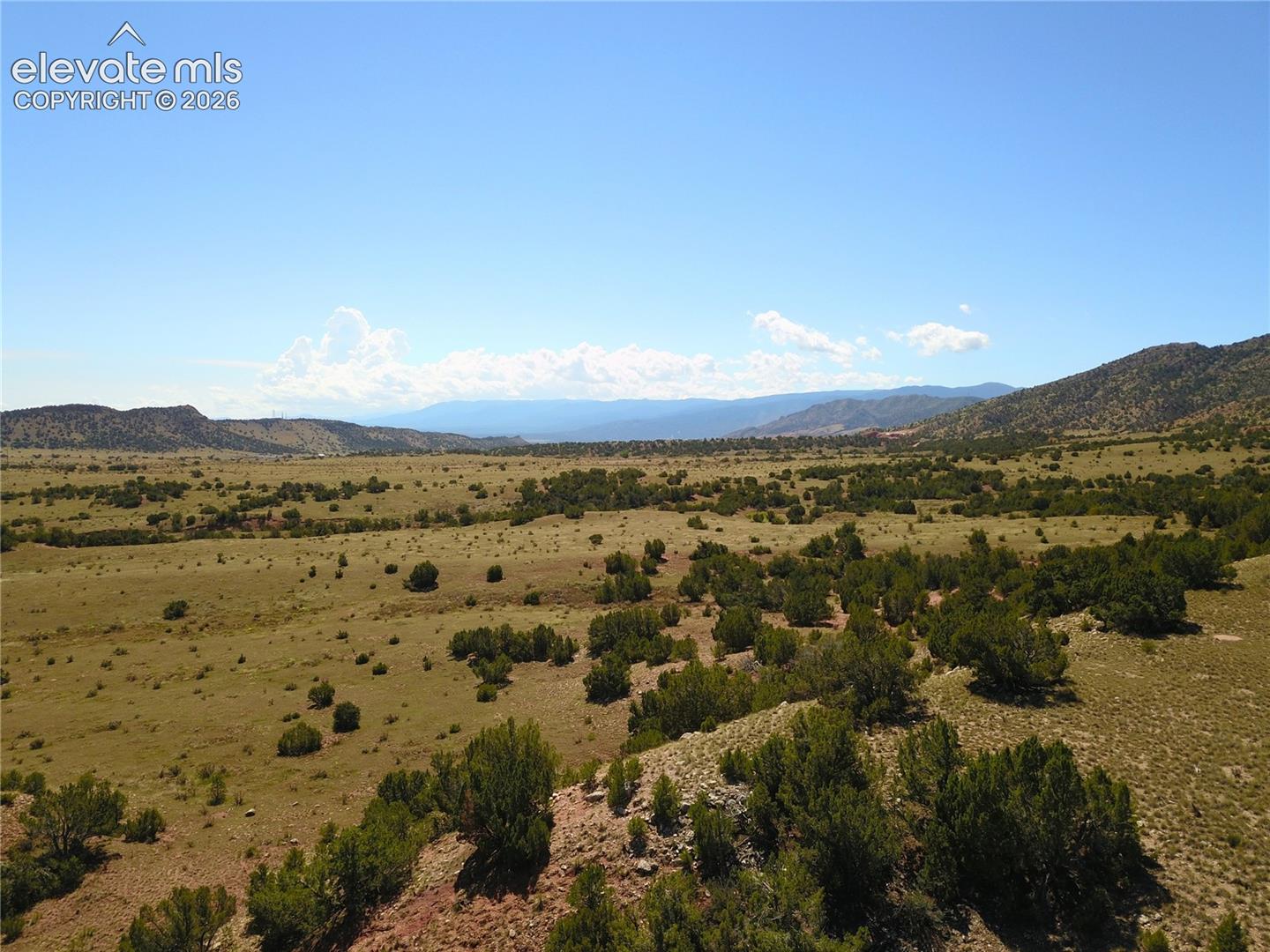 Expansive open landscape featuring natural vegetation and distant mountain ranges