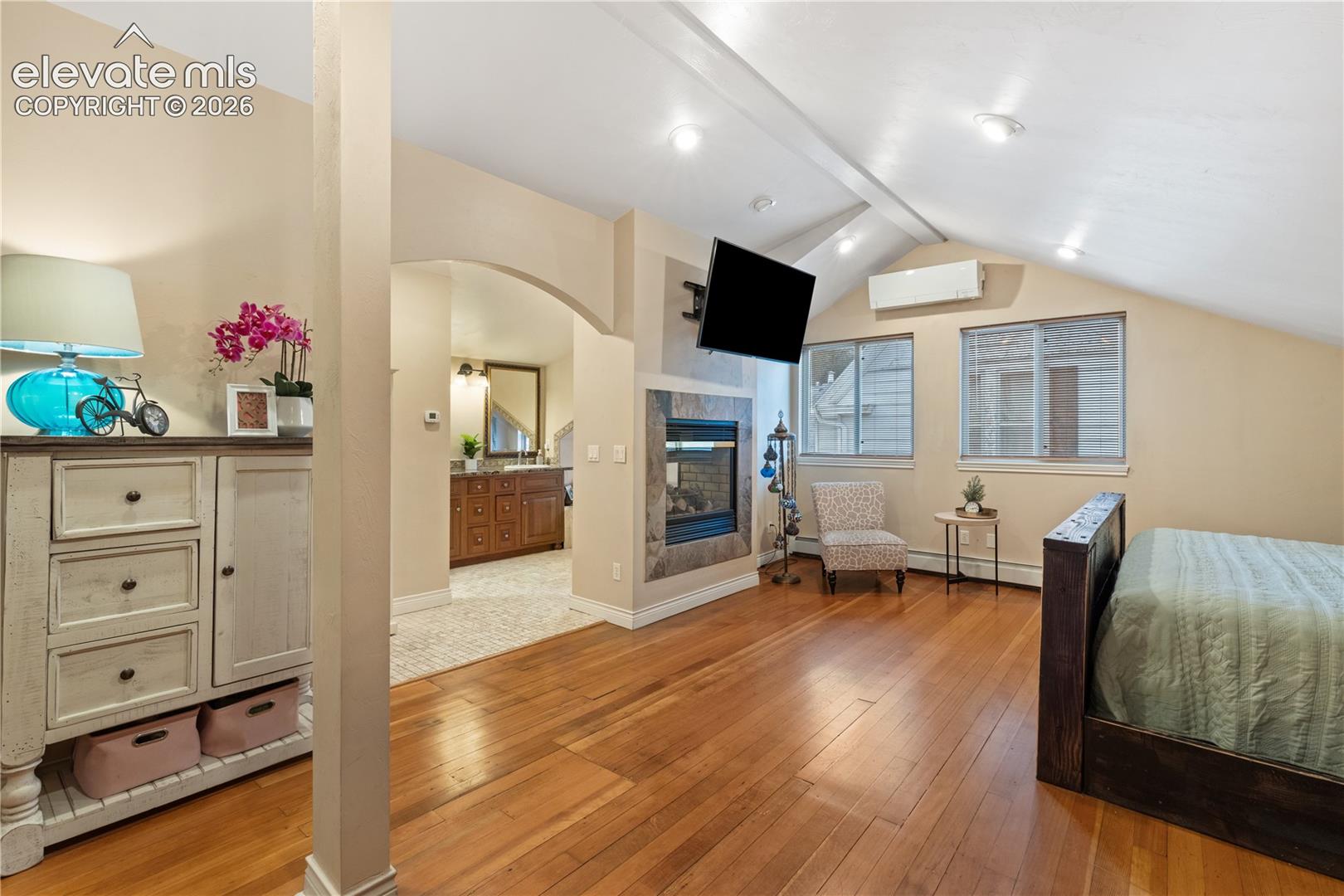 Hardwood flooring throughout the sleeping area, featuring a built-in fireplace with a stone surround