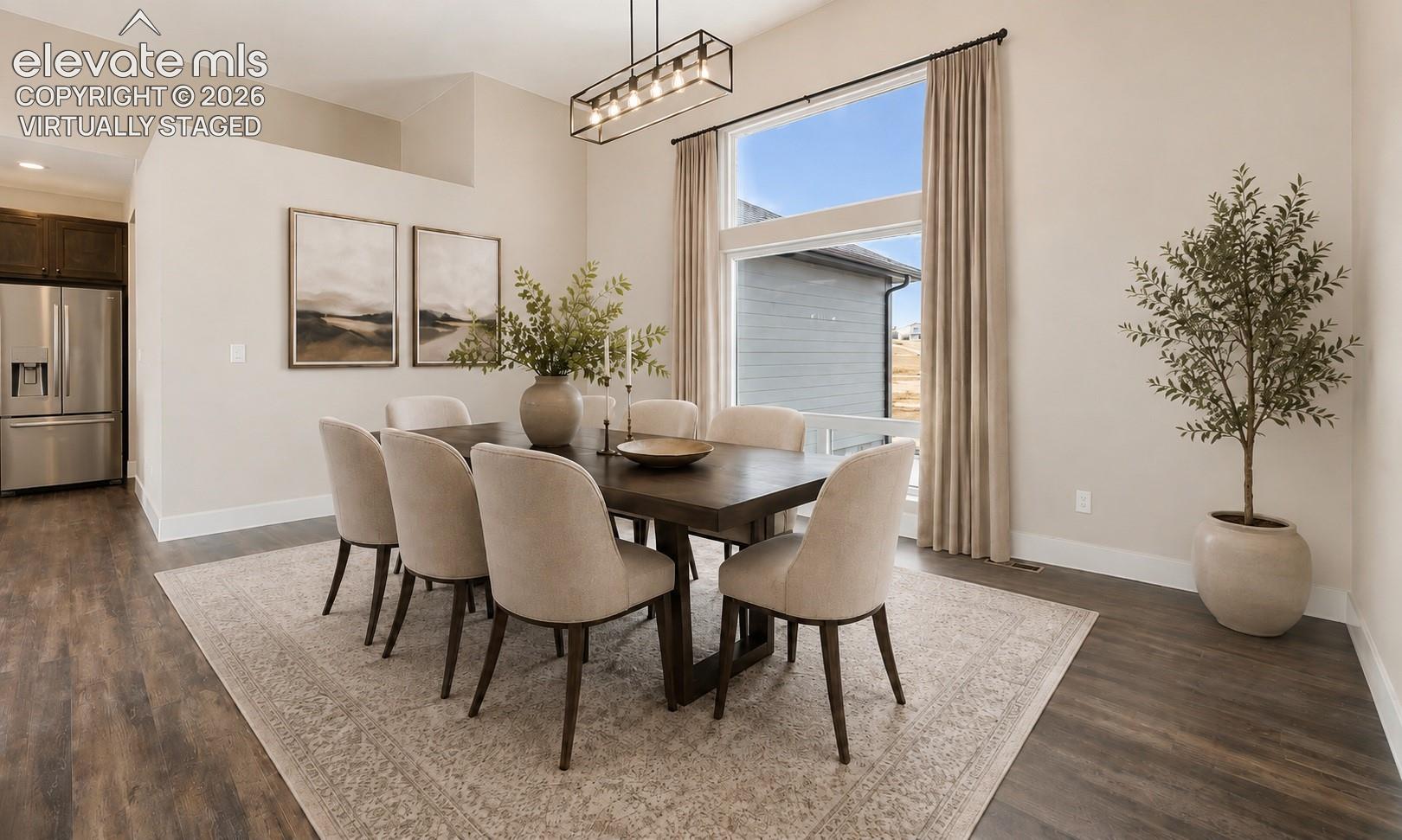 Virtually Staged Dining area featuring wood-finish flooring, a contemporary linear chandelier, and a large window with floor-to-ceiling drapery