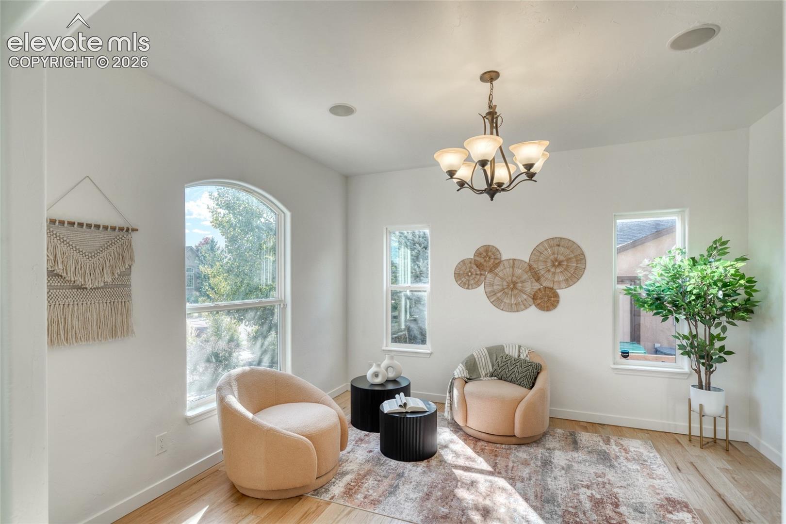 Recessed ceiling lighting, a five-light chandelier, archway detailing, wood-finish flooring, and multiple windows