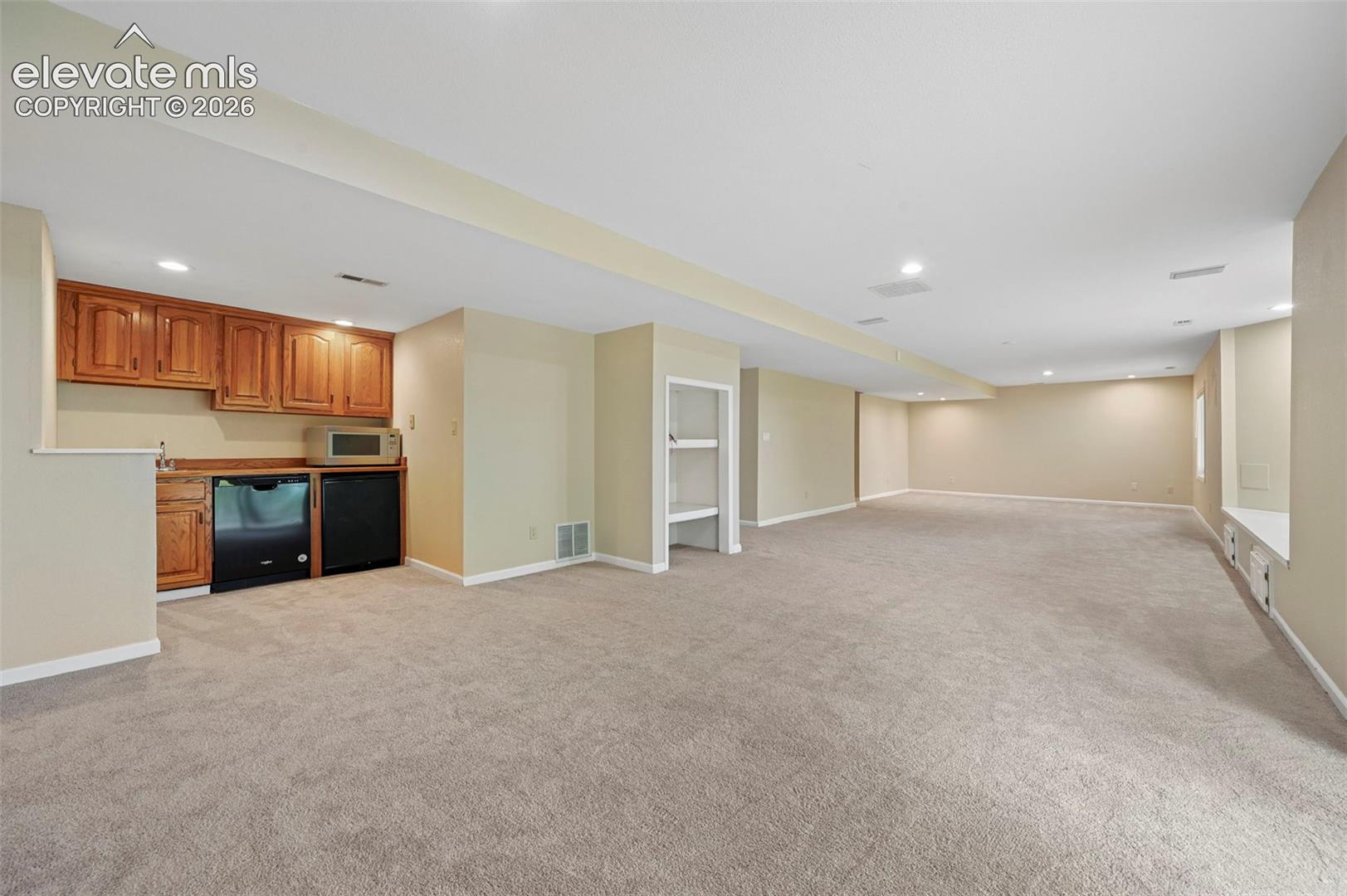 Unstaged basement family room with brick fireplace and wetbar, walkout to lower deck!   