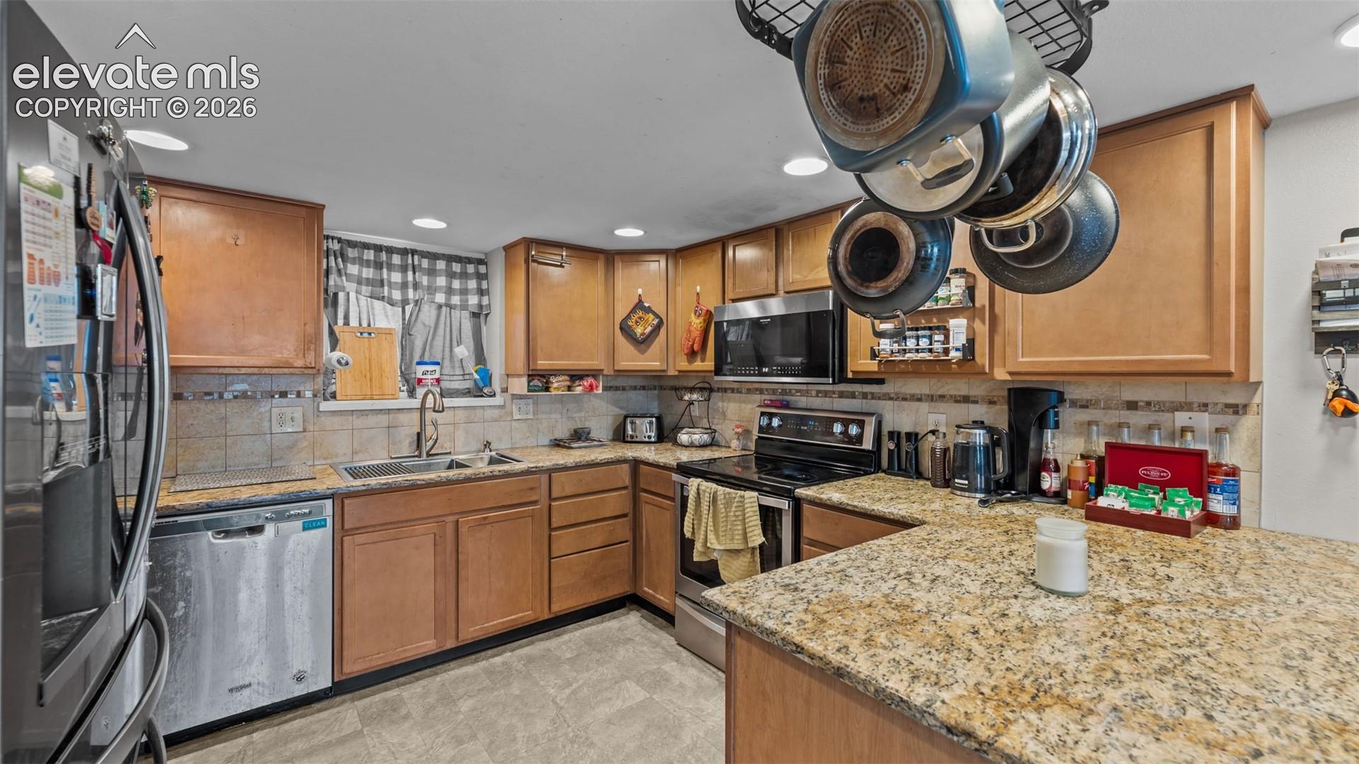 Kitchen featuring stone countertops, natural-finish wood cabinetry, stainless steel appliances, and a tiled backsplash