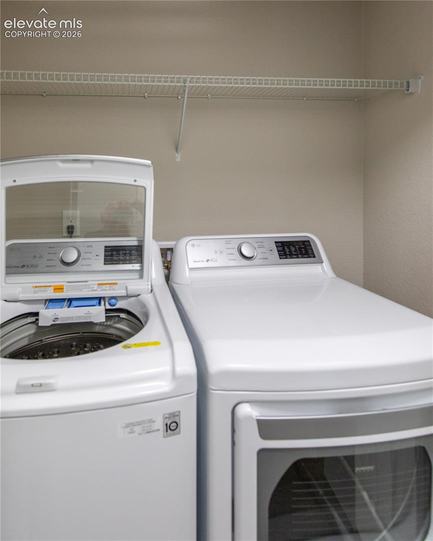 Laundry area featuring a top-load washer, front-load dryer, and an overhead wire shelving unit