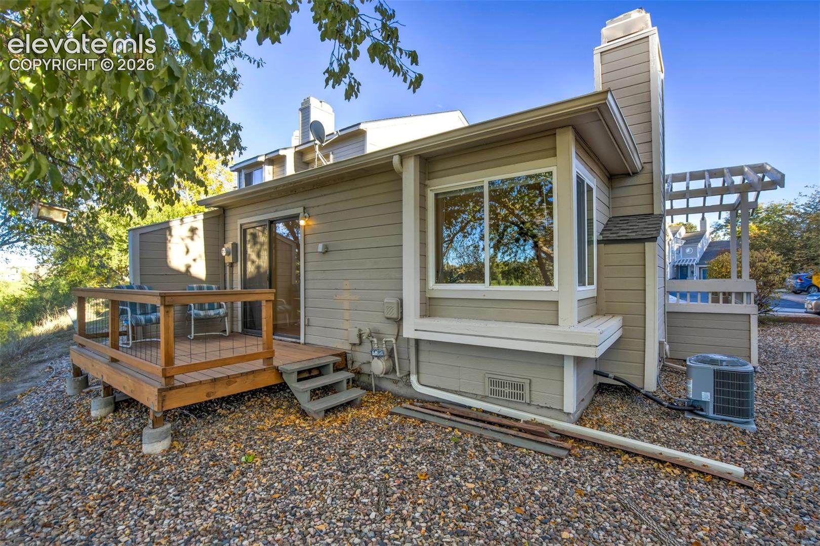 Exterior featuring lap siding, a raised wooden deck with wire railing, a box bay window, a chimney, and a wooden pergola structure