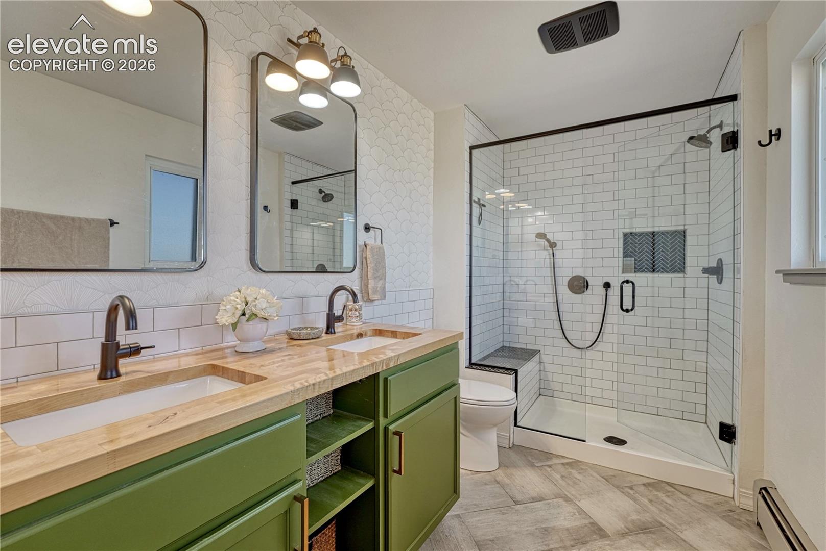 Remodeled primary bath with butcher block double vanity and tiled walk-in shower