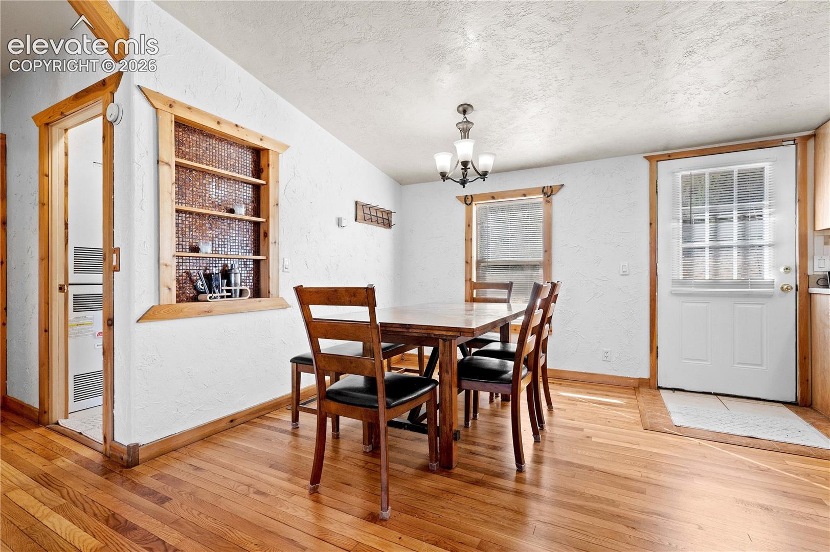 Dining room with hardwood / wood-style floors, a chandelier, a textured ceiling, and vaulted ceiling